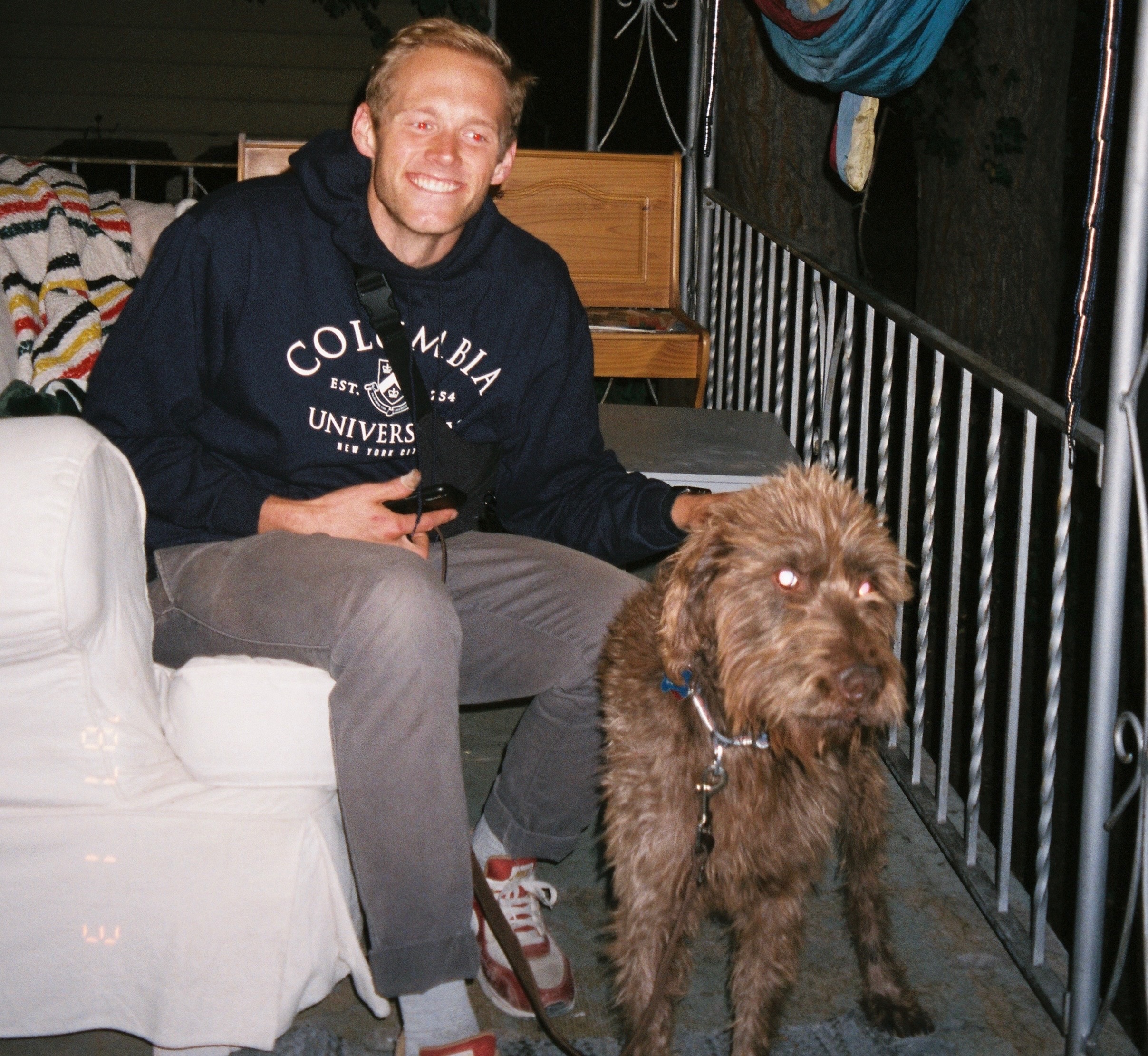 Chris Rytting sitting on a porch beside a scruffy brown dog